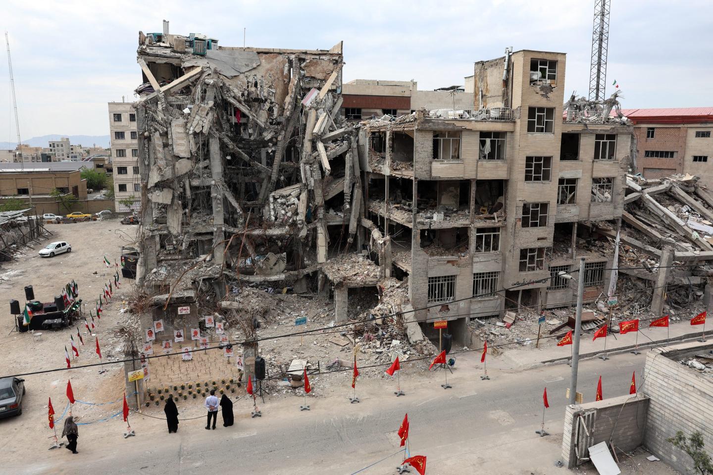 Iranians look at portraits of victims reportedly killed in a U.S.-Israeli air strike on the residential building near which they are displayed, in Tehran on April 13, 2026.