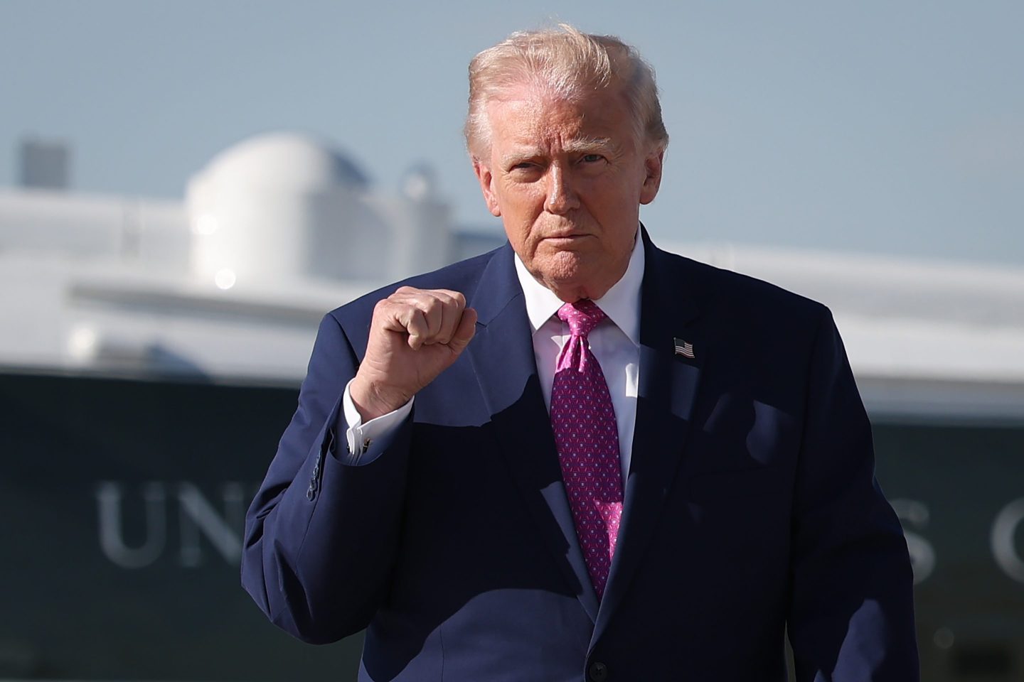 Donald Trump walks outside, putting a fist in the air.
