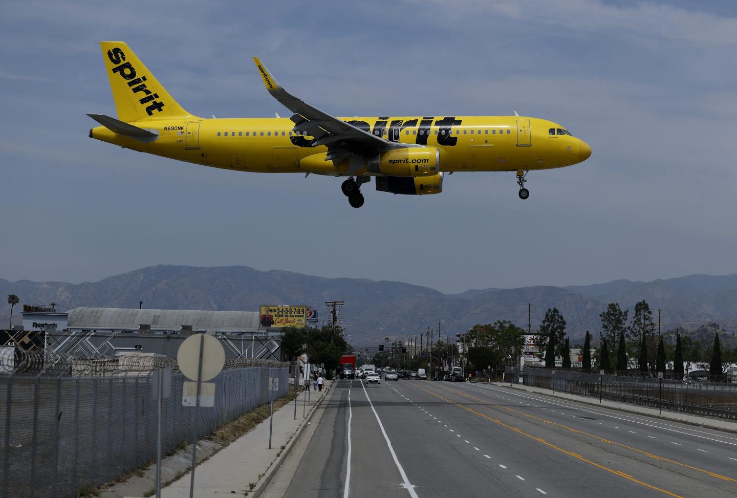 A Spirit Airlines plane flies over a highway