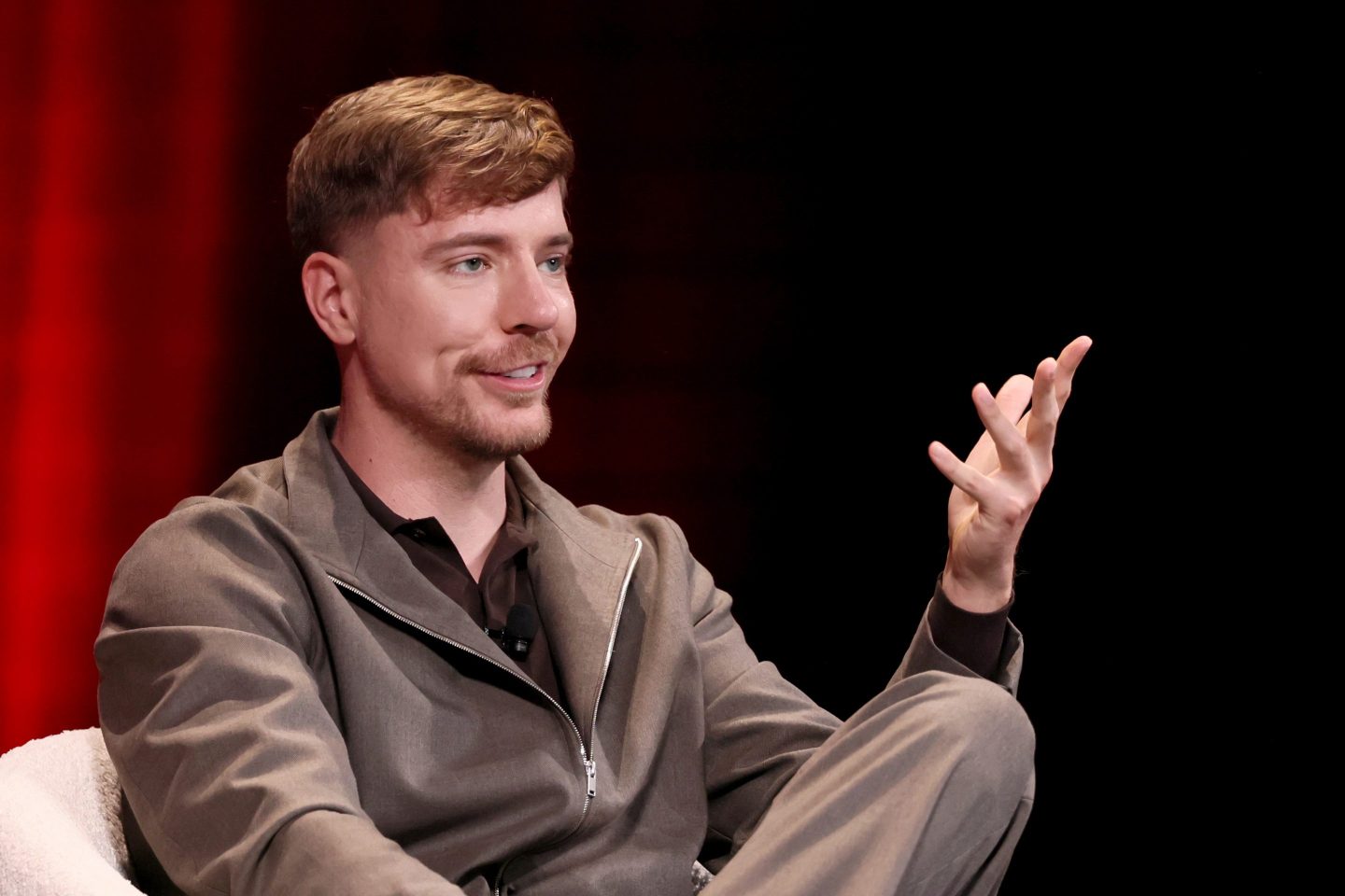 Jimmy Donaldson sits in a white chair in front of a red and black background.