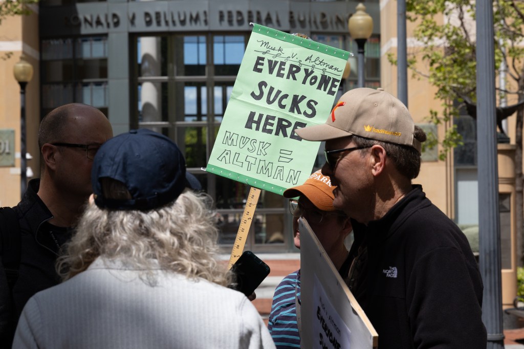 Demonstrators protest outside the courthouse as jury selection begins in the lawsuit between Elon Musk and OpenAI on April 27, 2026 in Oakland, California. (Photo: Benjamin Fanjoy/Getty Images)