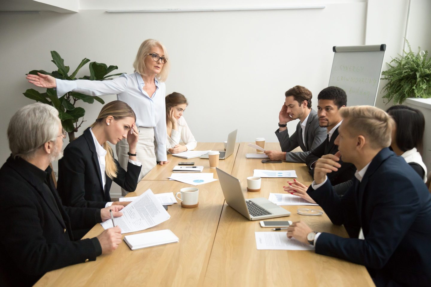 A group of people at a boardroom table, with one person standing