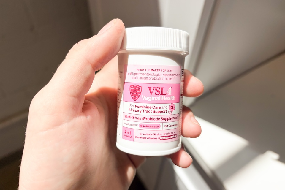 A hand holding a bottle of VSL4 Vaginal Health probiotics.