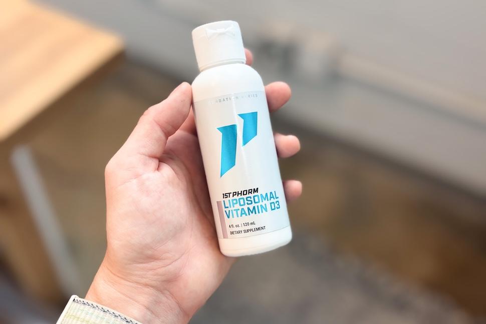 A hand holding a bottle of 1st Phorm Liposomal Vitamin D3