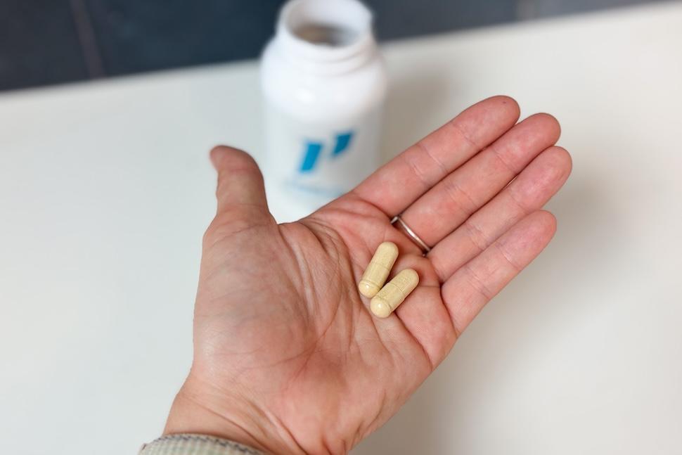An open palm holding two 1st Phorm Prenatal Plus capsules