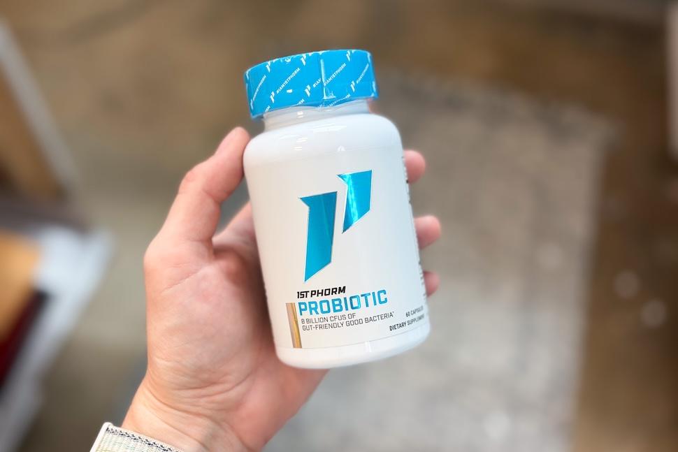 A closeup of a hand holding a bottle of 1st Phorm Probiotic