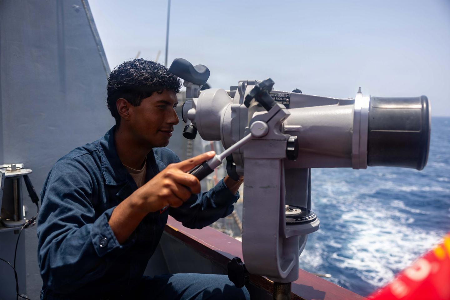 Sailor scans the horizon for surface vessels on the bridge of Arleigh Burke-class guided-missile destroyer USS Rafael Peralta (DDG 115) as it patrols the Arabian Sea enforcing a maritime blockade against ships entering or exiting Iranian ports and coastal areas, May 18, 2026.