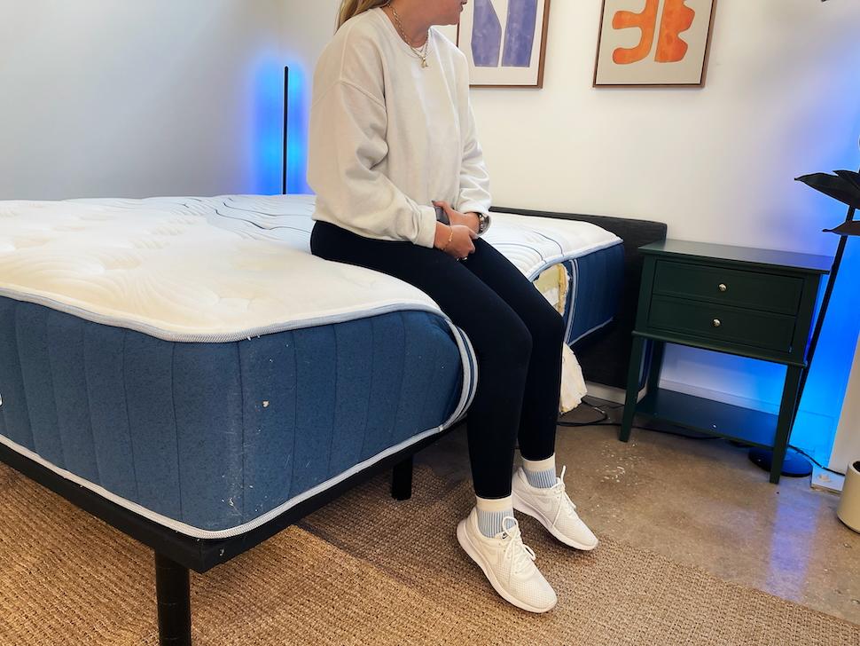 A woman sitting on the edge of the Bear Elite Hybrid mattress