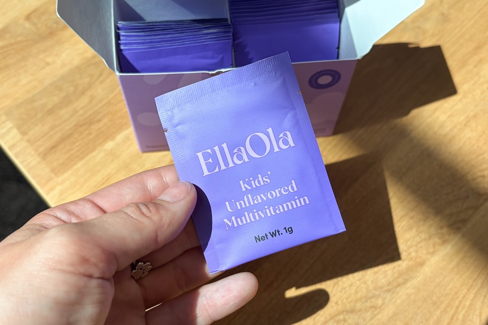 Closeup of a hand holding a purple packet of EllaOla Teens’ Essential Unflavored Multivitamin