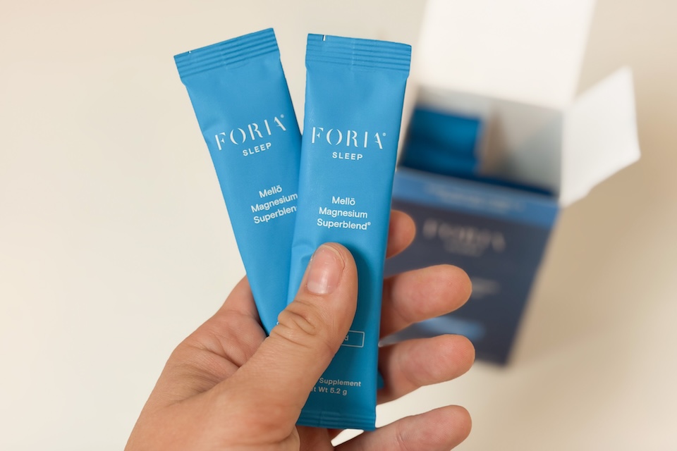 A hand holding up two packets of Floria Sleep Mello Magnesium.