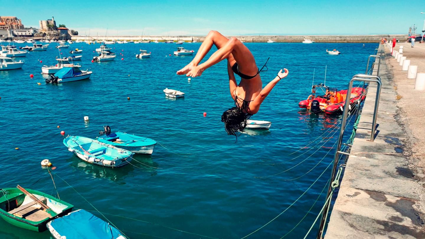 Girl doing backflip into the ocean.