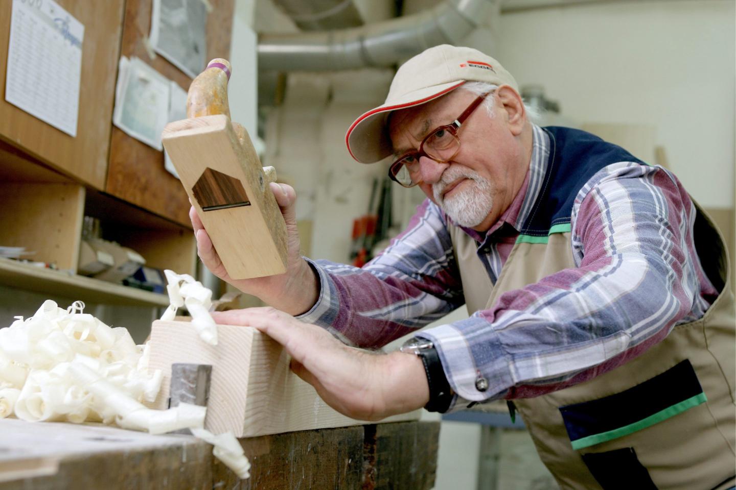 A man shaves wood pieces from a block.