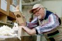 A man shaves wood pieces from a block.