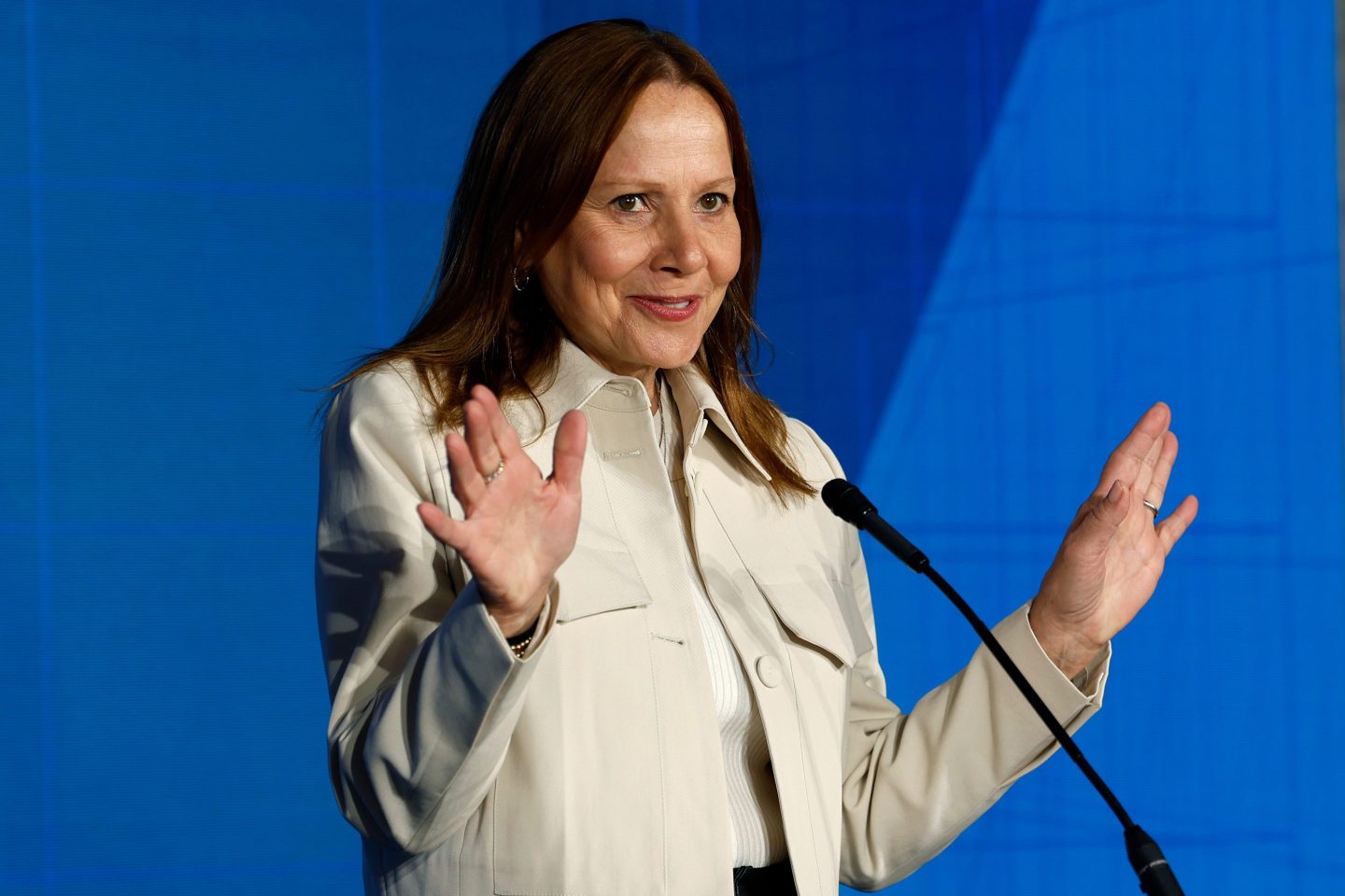 Mary Barra with both her hands up in front of a microphone
