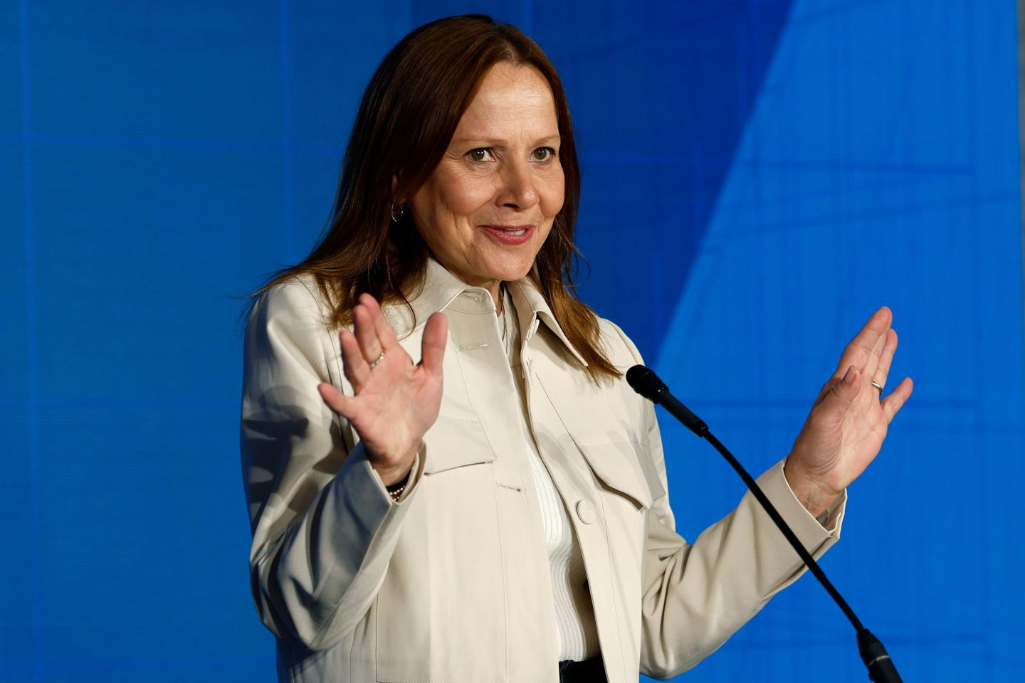 Mary Barra with both her hands up in front of a microphone