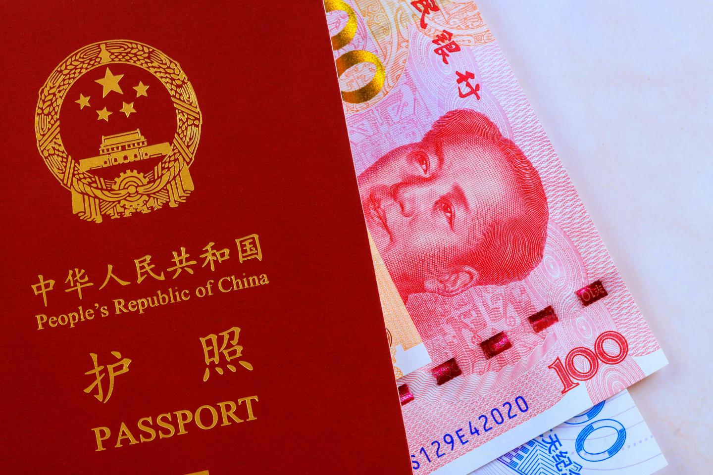A passport issued by the People's Republic of China and Chinese currency banknotes. (Photo: iStock/Getty Images)