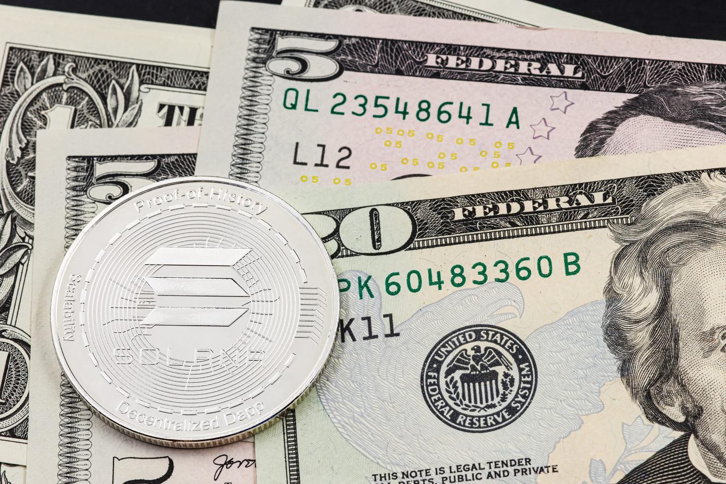 A Solana token sits on top of several cash bills