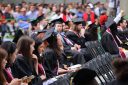 College graduates sitting at commencement yell.