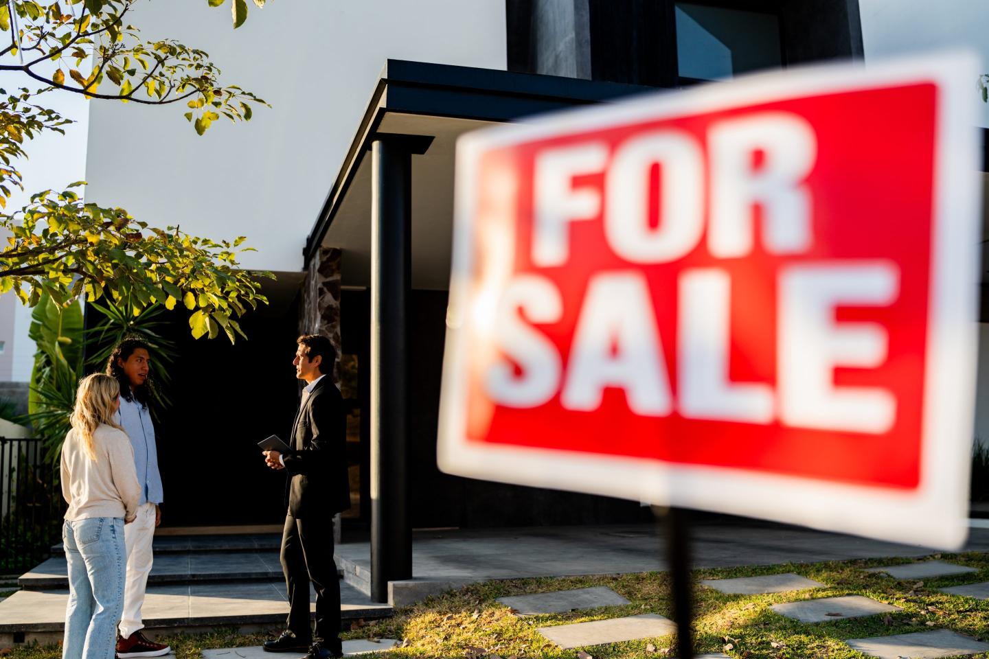 Mid adult real estate agent talking to couple at a house for sale