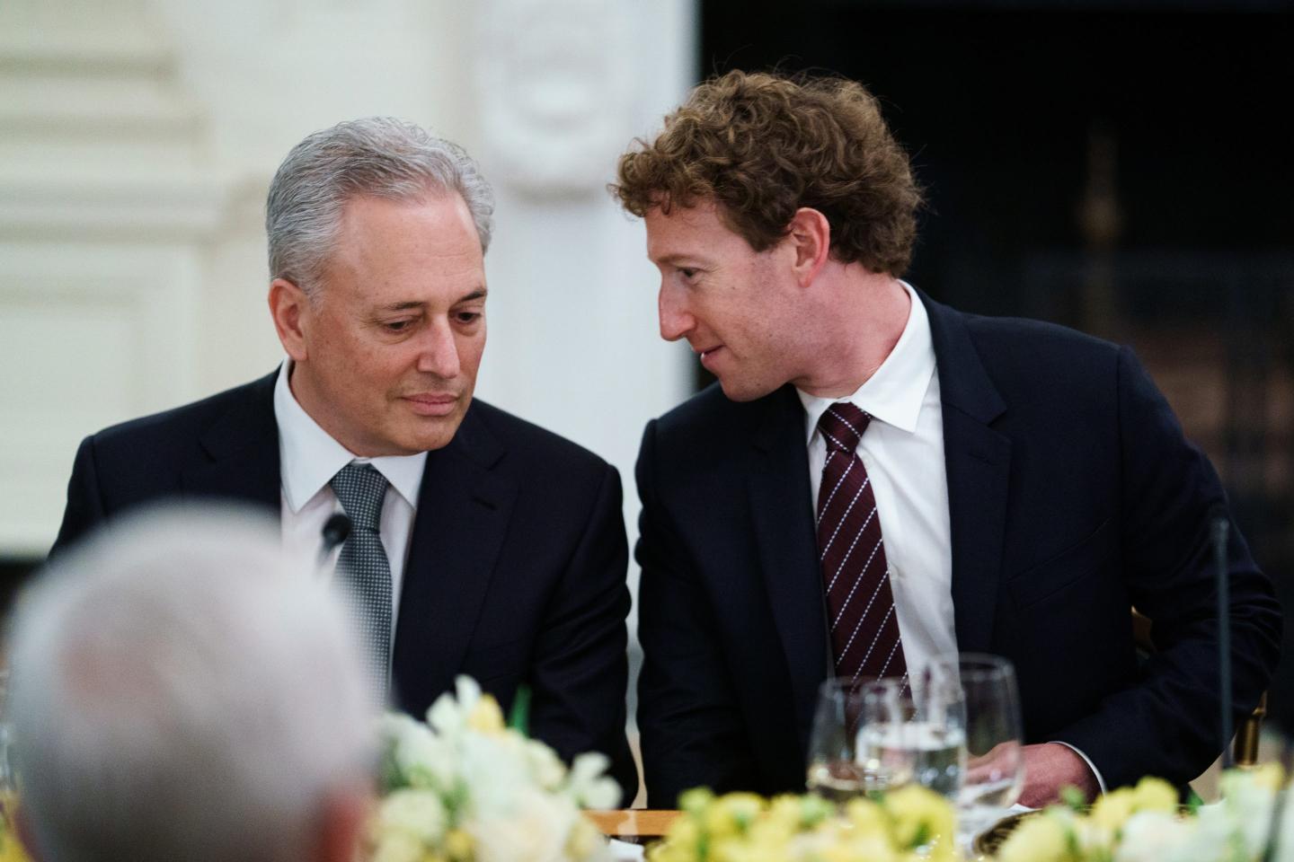 Trump AI and crpto czar David Sacks sits next to Meta CEO Mark Zuckerberg at a dinner table in the White House as Zuckerberg turns to Sacks and says something.