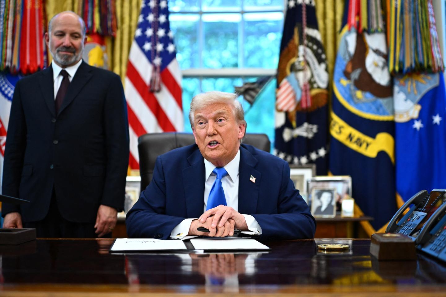 US President Donald Trump speaks before signing an executive order in the Oval Office at the White House in Washington, DC, as Commerce Secretary Howard Lutnick looks on.