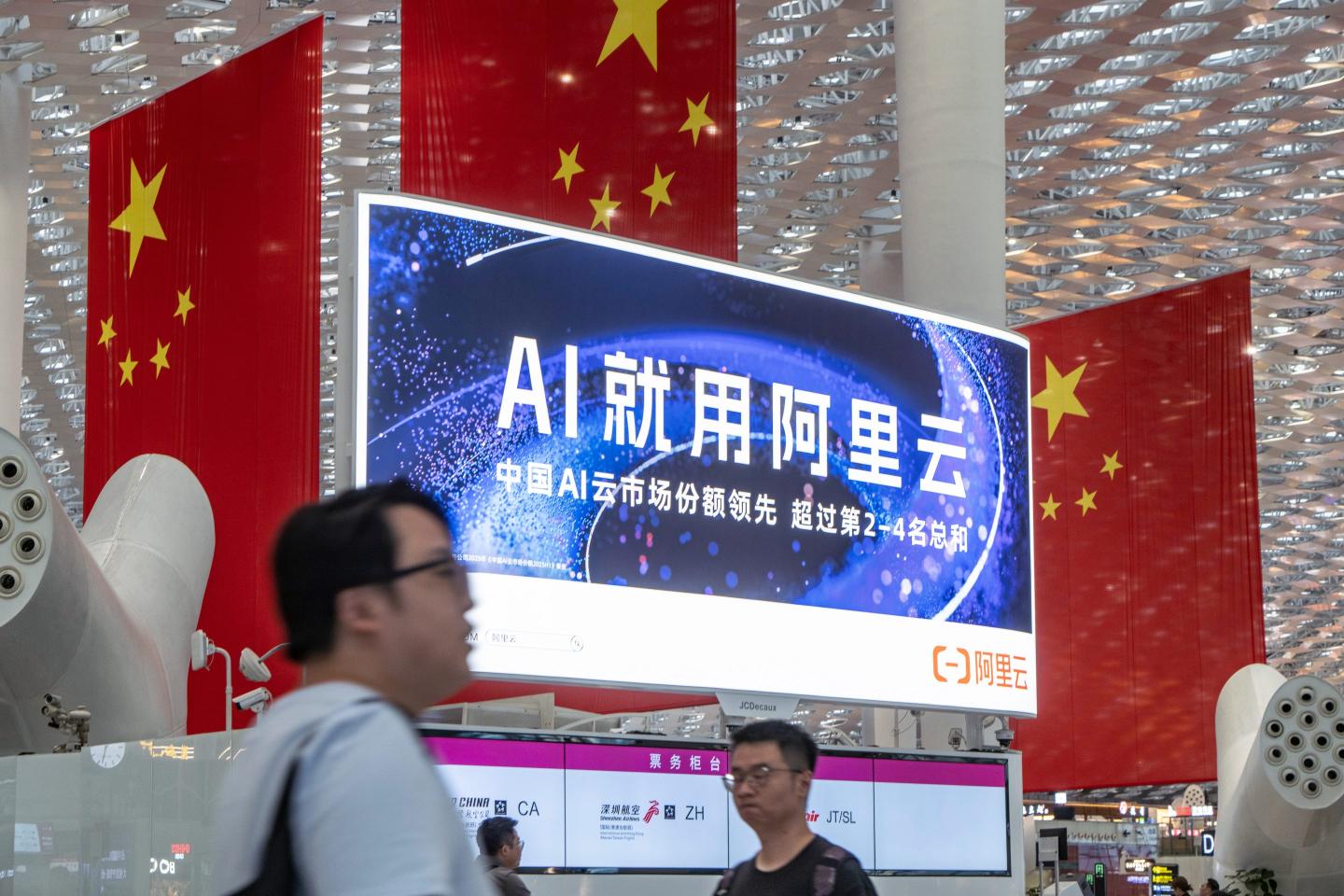 Travelers walk past an Alibaba Cloud advertisement in China