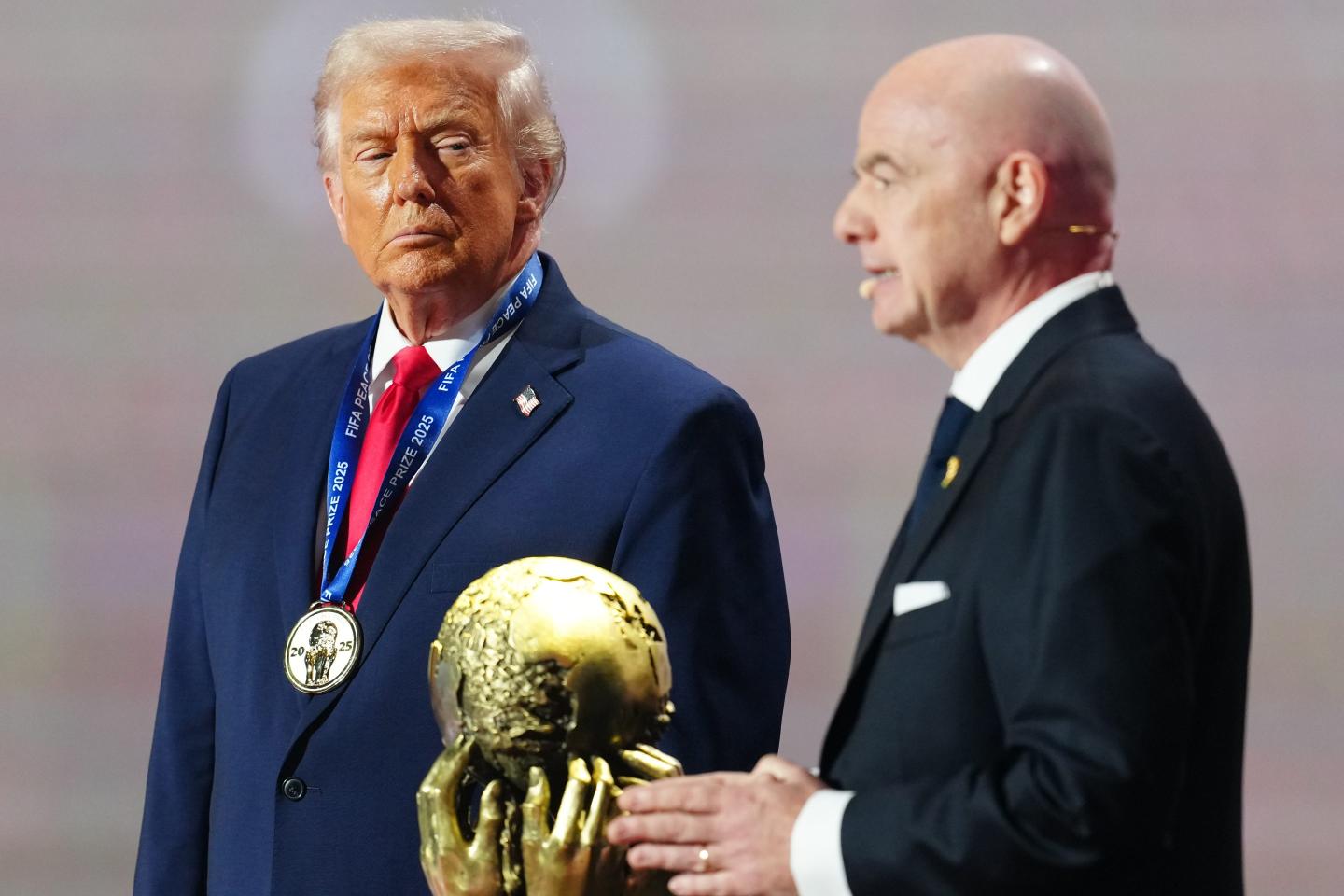 Donald Trump looks at FIFA President Gianni Infantino with the FIFA Peace Prize in front of them both.