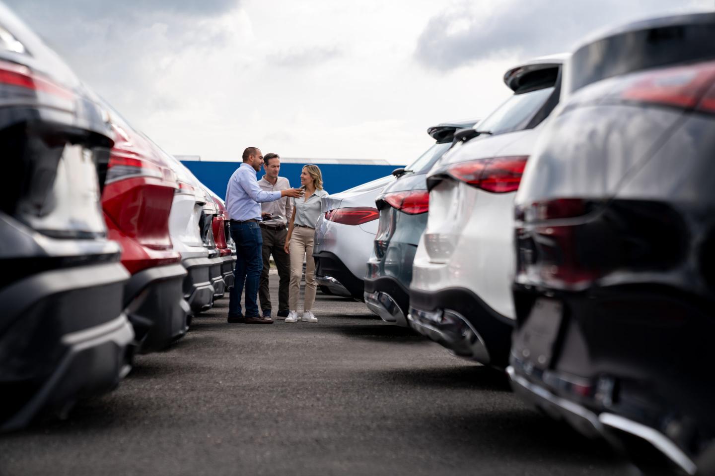 Car salesperson showing cars to a couple shopping at the dealership