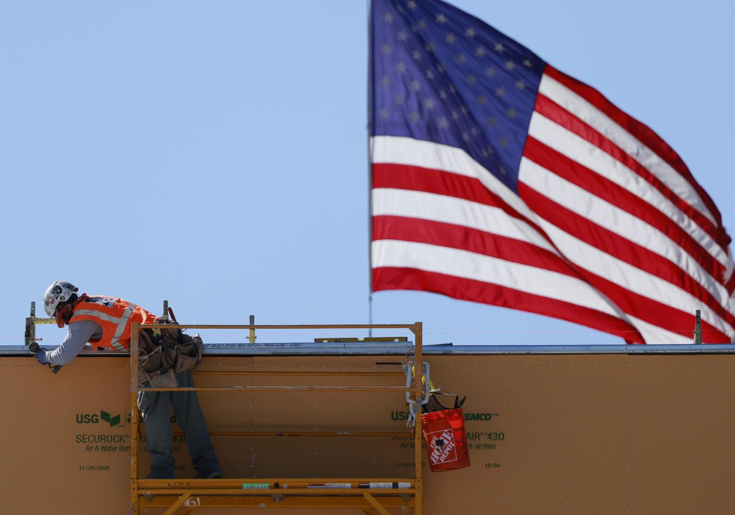 An American flag flies near a construction worker during construction of a new building on March 6, 2026 in Pasadena, California.