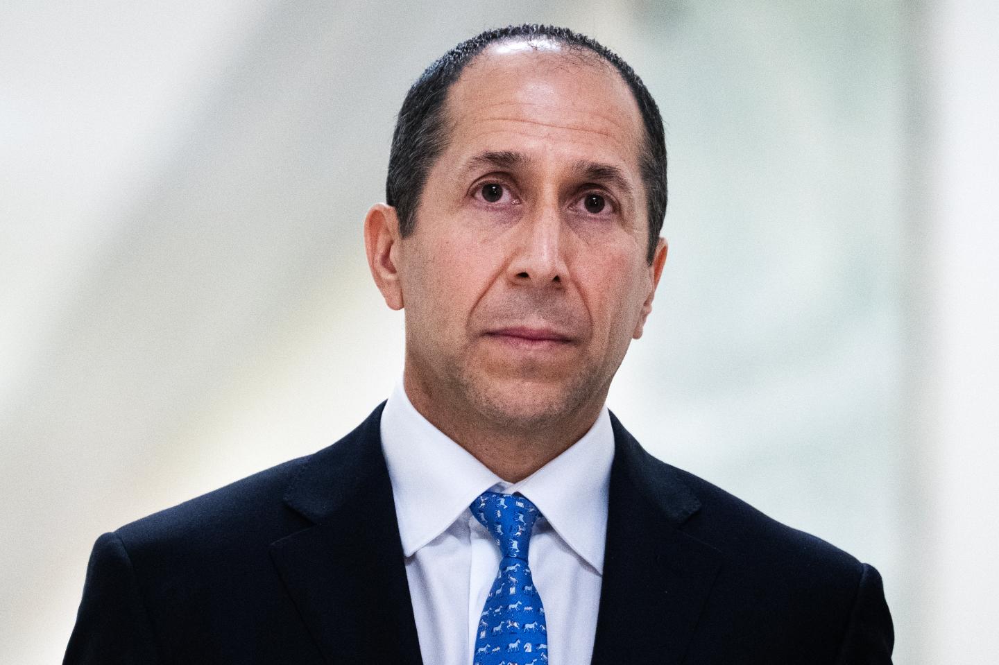 Richard Kahn wears a suit and frowns.