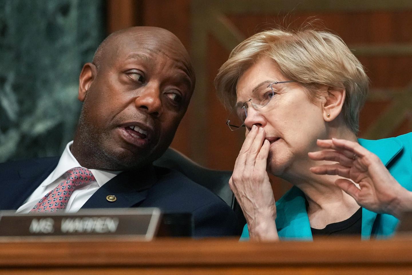 Sens. Tim Scott (R-S.C.) and Elizabeth Warren (D-Mass.) whisper to each other during a Senate committee meeting