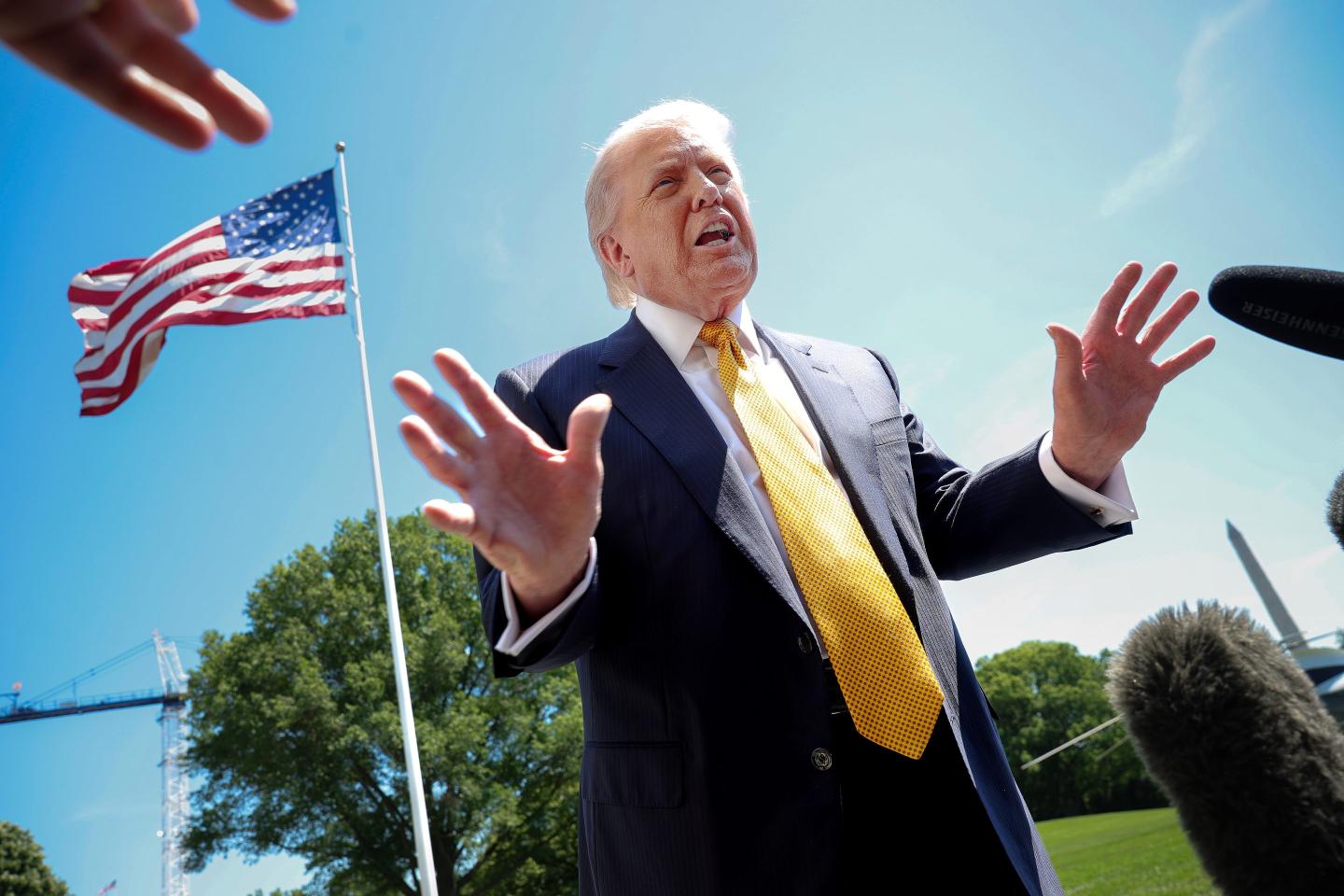 U.S. President Donald Trump speaks in front of the American flag to the press as he departs the White House on May 12, 2026 in Washington, DC.