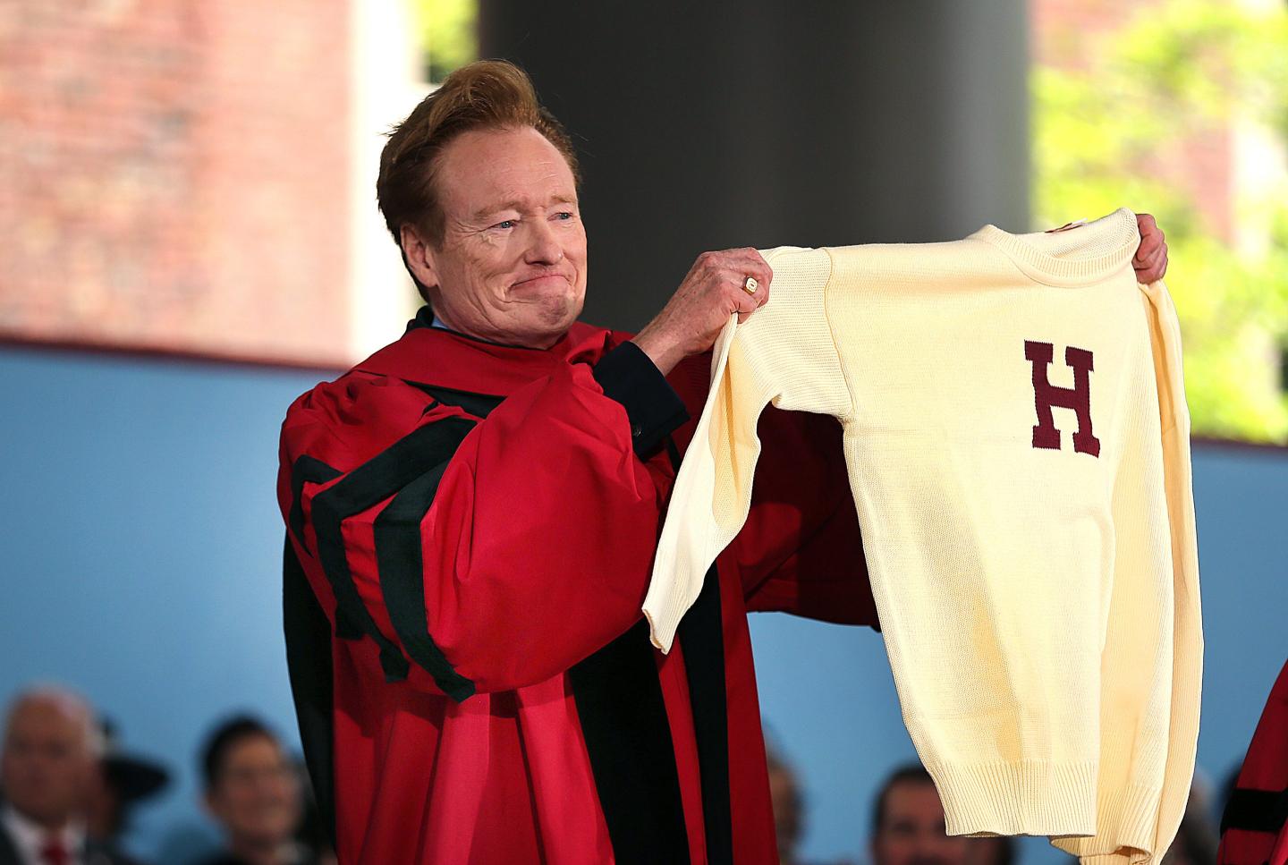 Conan O'Brien holds up a Harvard sports sweater given to him after he delivered the commencement address at Harvard University