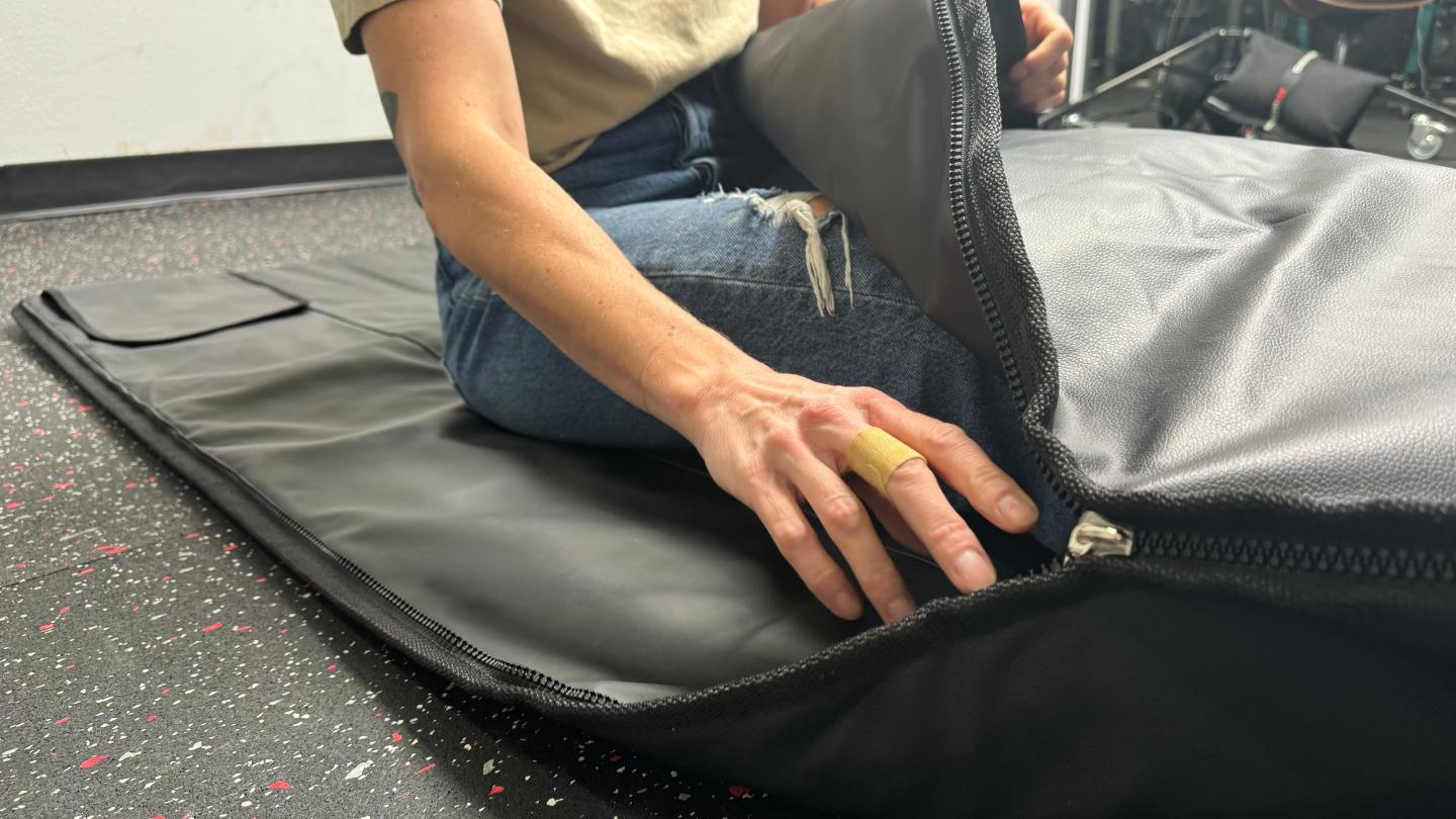 A closeup of a woman's hand touching the zipper of the HigherDOSE Infrared Sauna Blanket