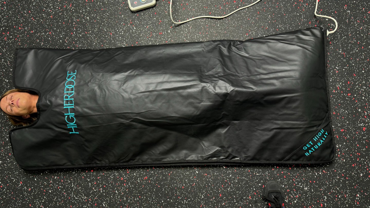 An overhead shot of a woman tucked into the HigherDOSE Infrared Sauna Blankt