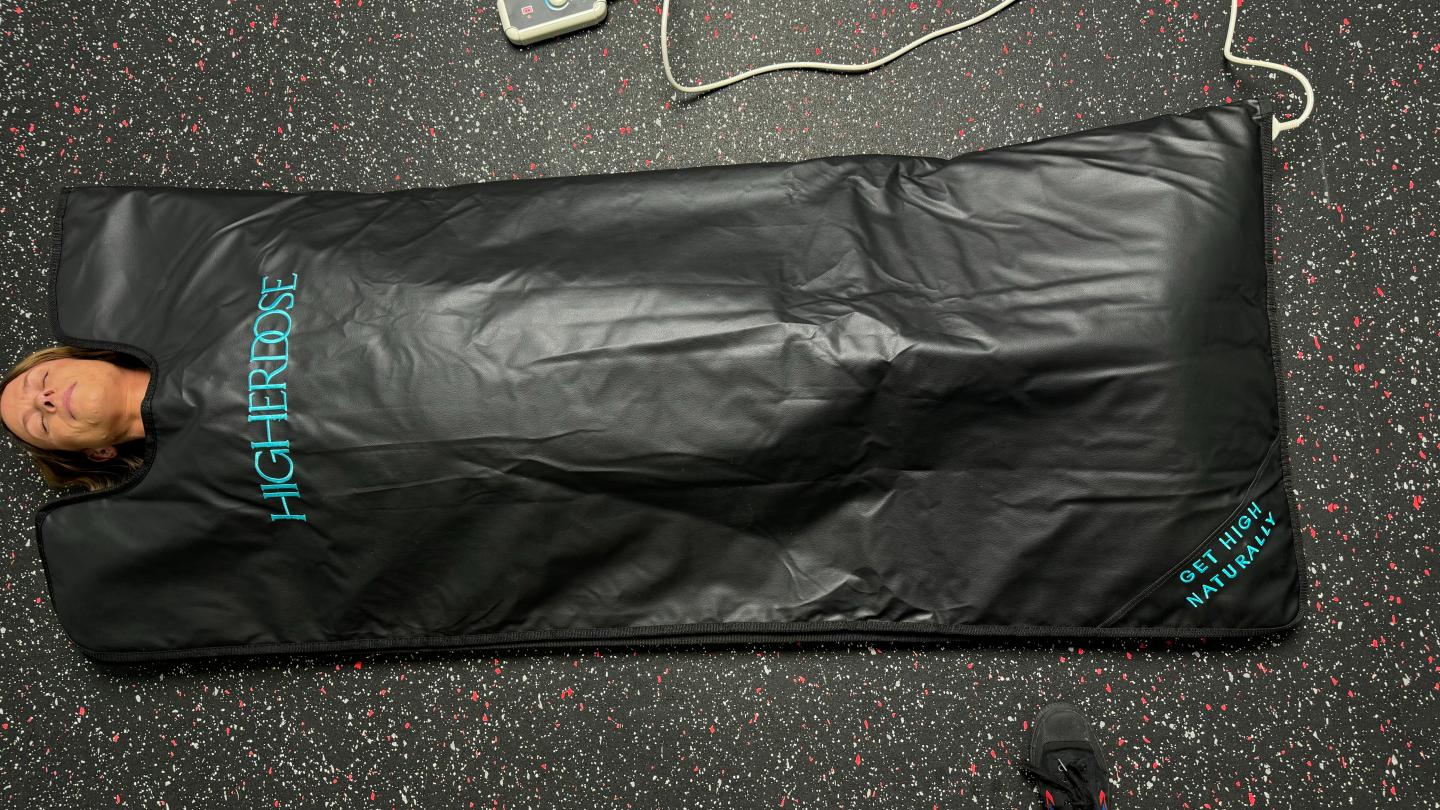 An overhead shot of a woman tucked into the HigherDOSE Infrared Sauna Blankt