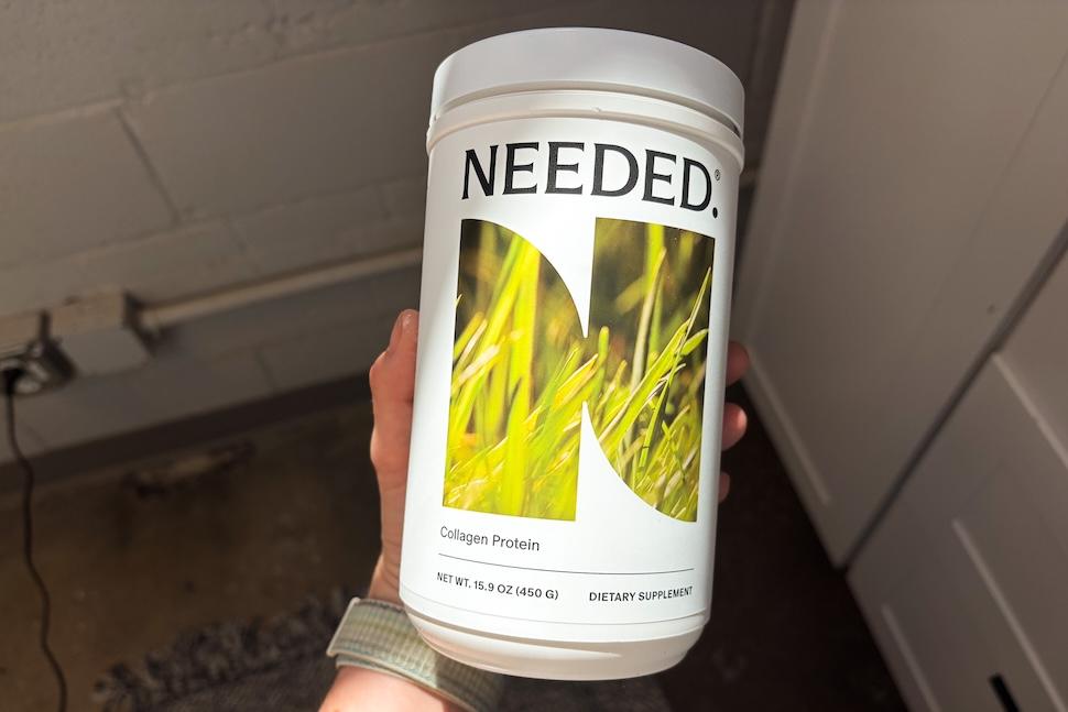 A hand holding a canister of Needed Collagen Protein