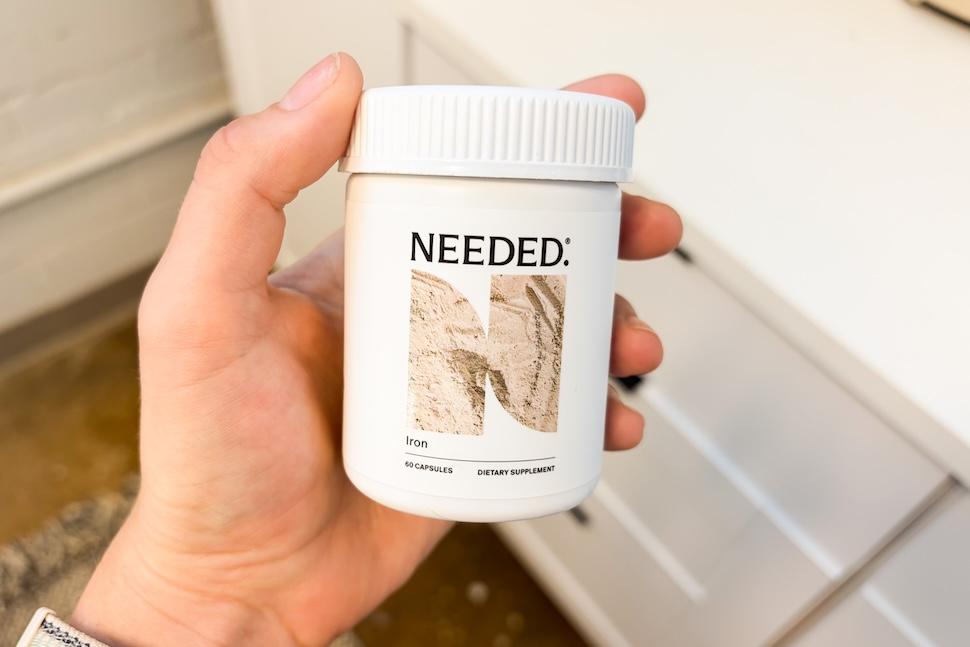 A hand holding a bottle of Netal Prenatal Iron supplements.