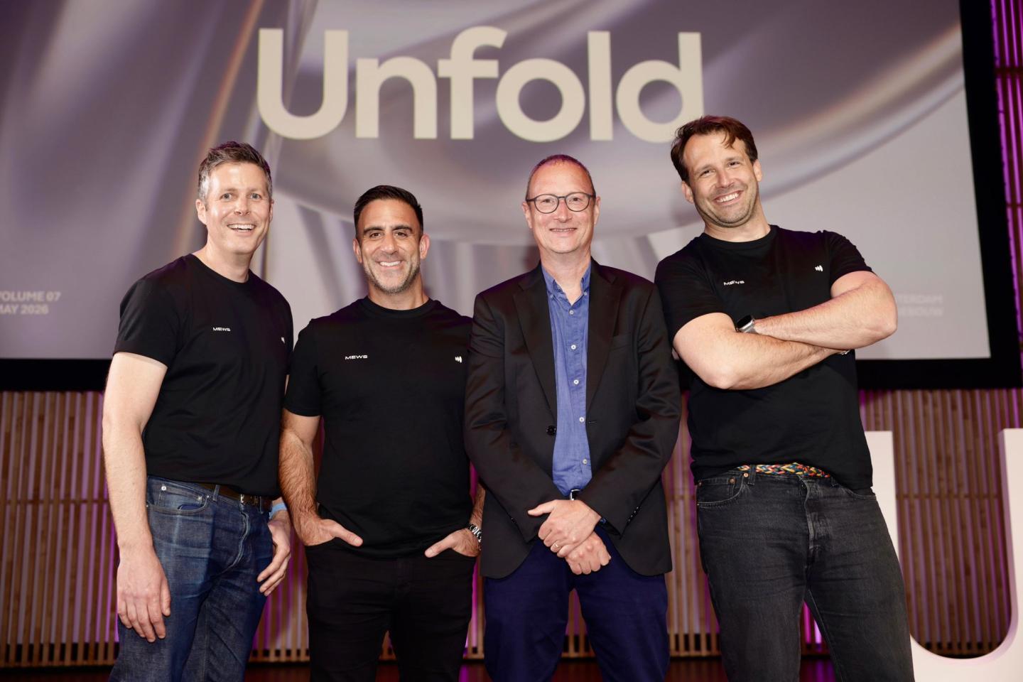Four men in a row smiling at the camera.