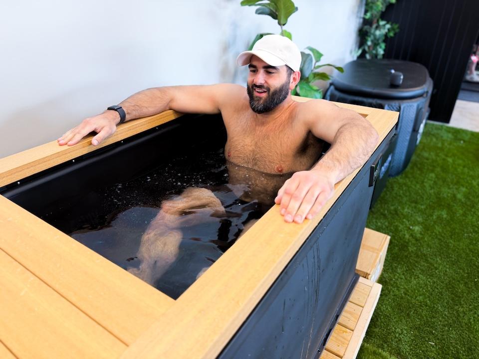 A man sitting in the Renu Cold Stoic 3.0. He has his arms up on the sides of the tub and is smiling.