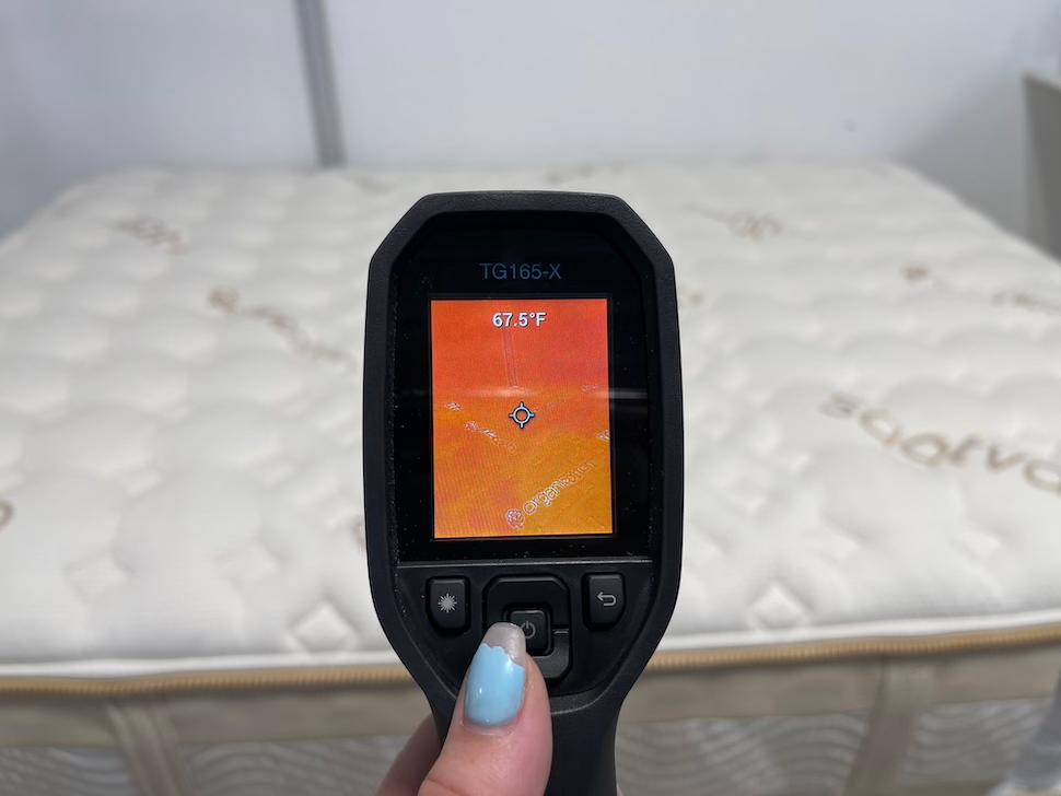 A closeup of a thermal gun showing the temperature reading of the Saatva Rx mattress. The screen reads 67.5 degrees.