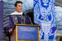 Tom Brady wearing commencement regalia behind a podium at Georgetown University