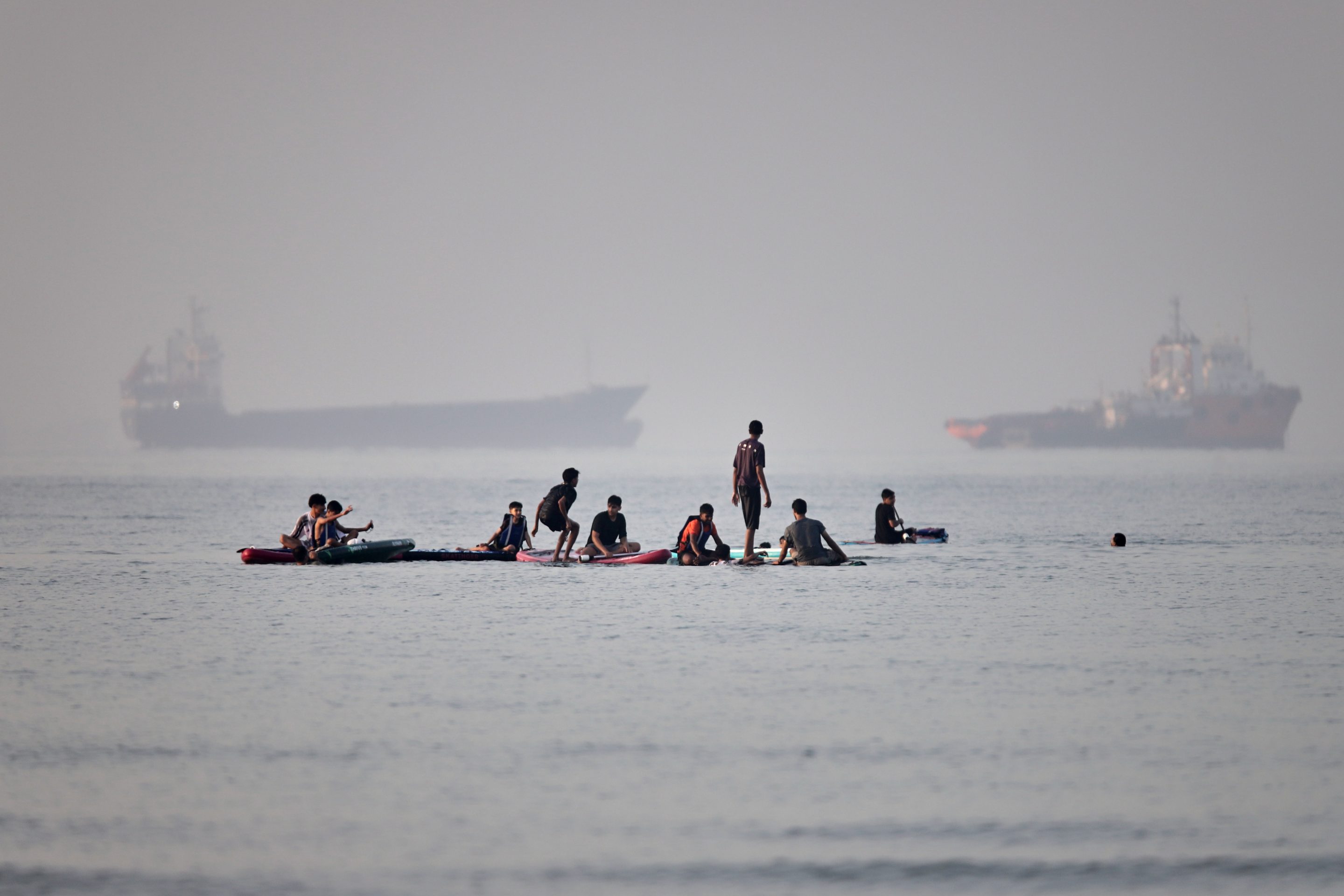 People gather on paddleboards in shallow water as cargo and service vessels are anchored in the Strait of Hormuz off Bandar Abbas, Iran, Monday, June 1, 2026. 