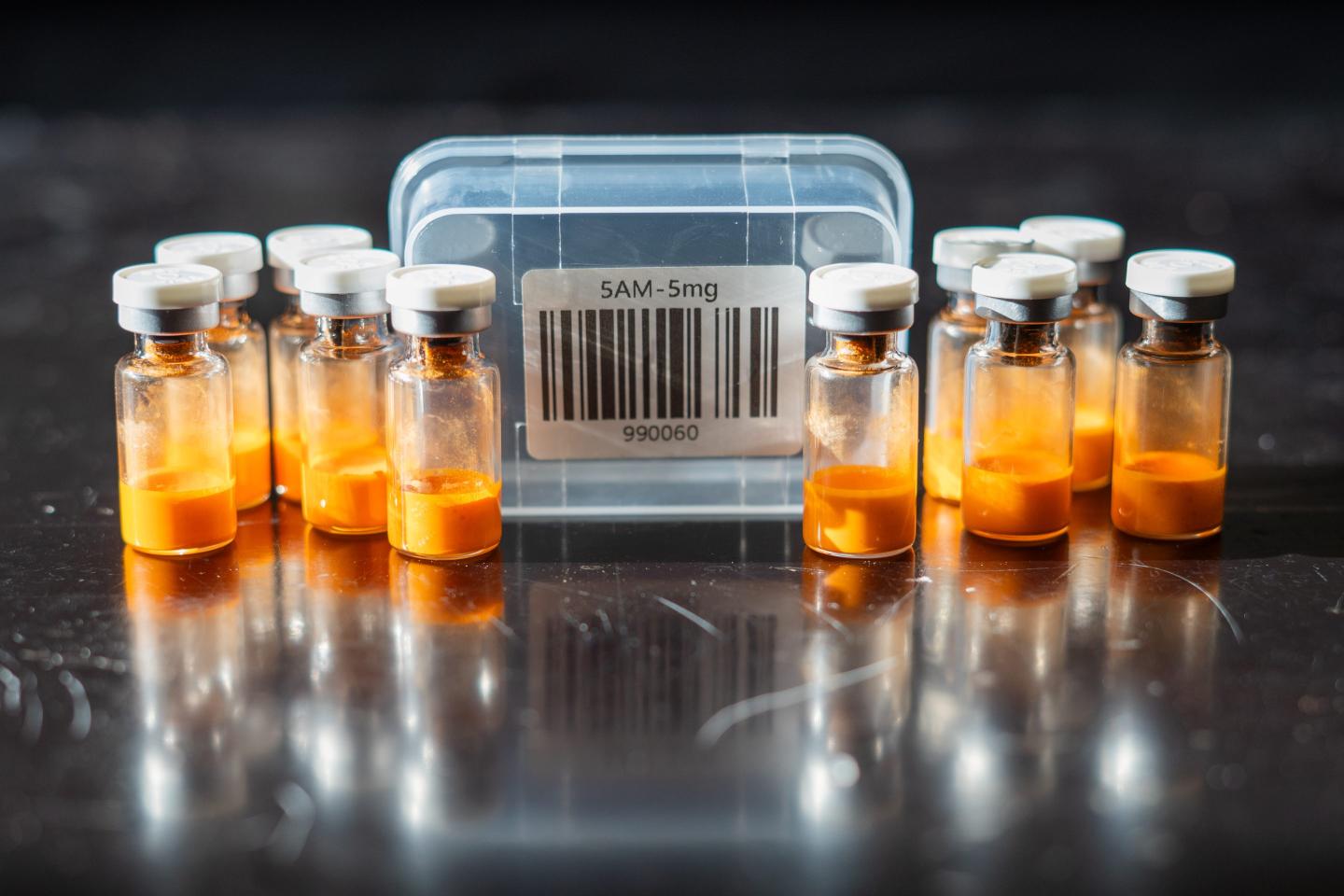 The label from a box of peptides next to 10 vials of an orange substance.