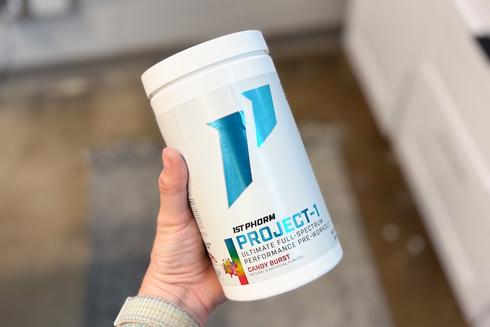 Closeup of a hand holding a canister of 1st Phorm Project-1