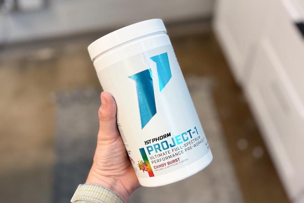 Closeup of a hand holding a canister of 1st Phorm Project-1