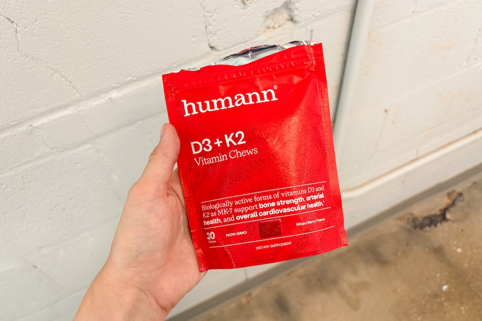 A hand holding a red bag of Humann D3 + K2 vitamin chews
