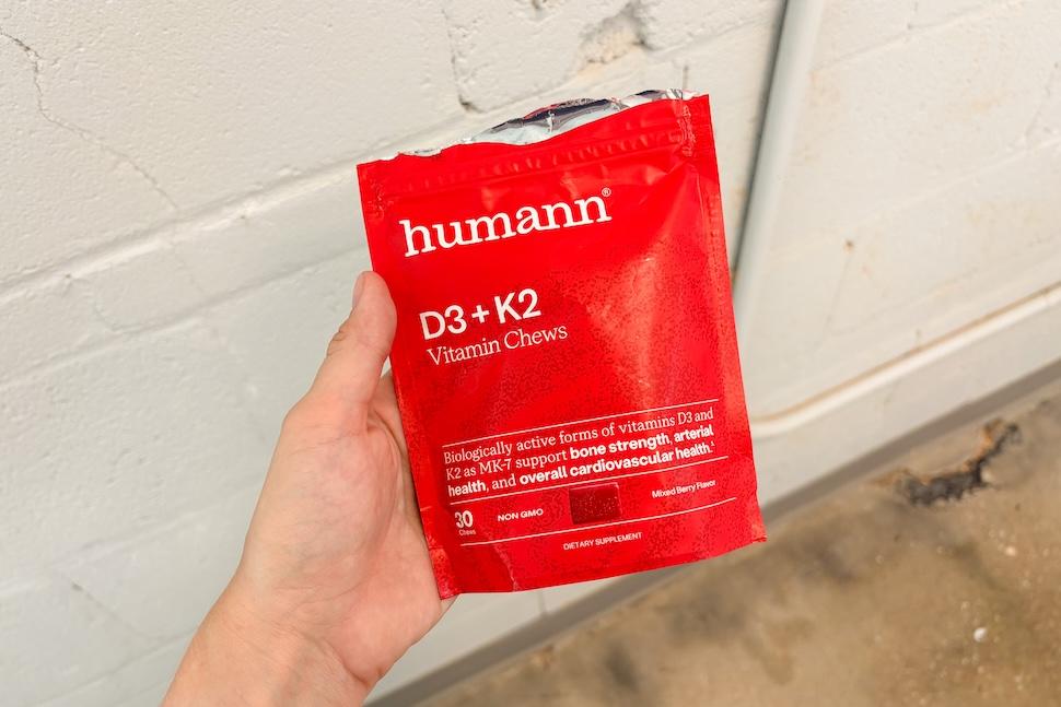 A hand holding a red bag of Humann D3 + K2 vitamin chews