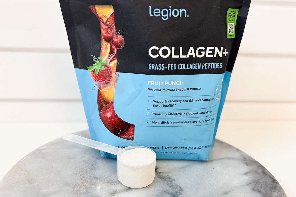 A bag of Legion Collagen+ sitting on a marble tabletop. A plastic scooper sitting next to it has been packed with white power.
