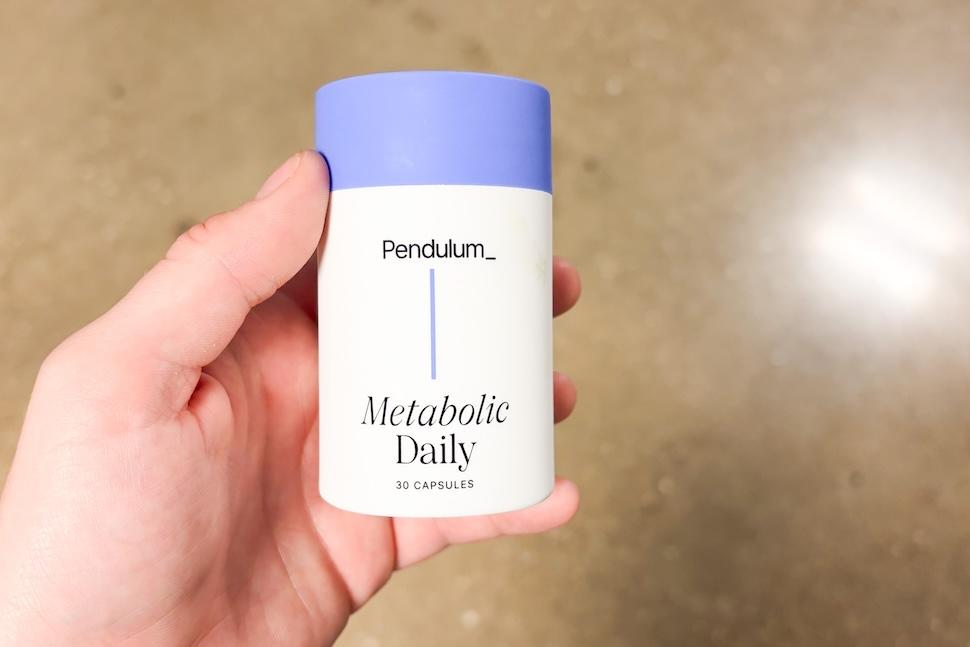 Closeup of a hand holding a bottle of Pendulum Metabolic Daily